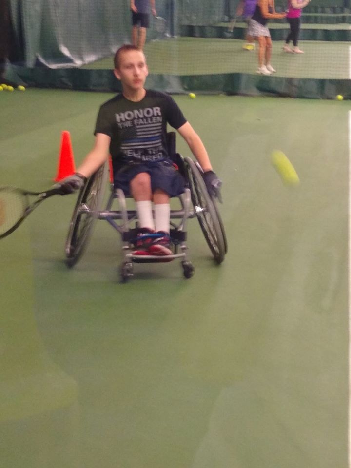 Male athlete in a wheelchair holding a tennis racket