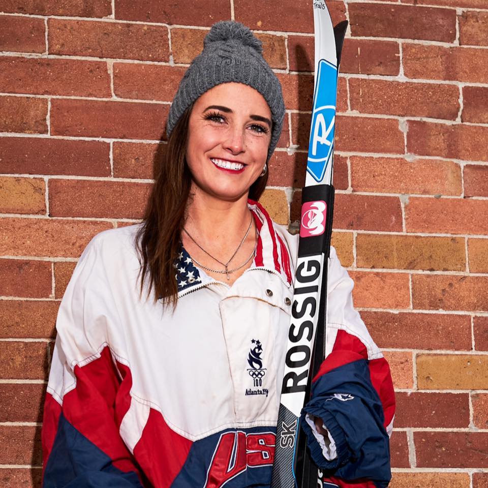 Female athlete smiling at the camera and holding snow skis