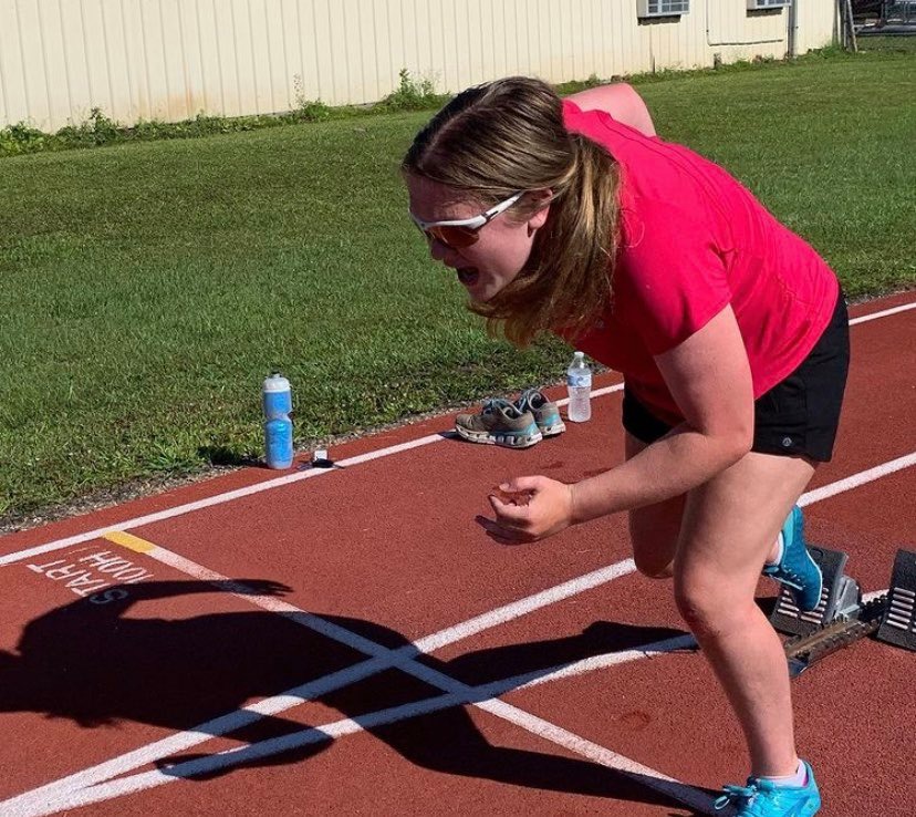 Female athlete on a track pushing off of starting blocks