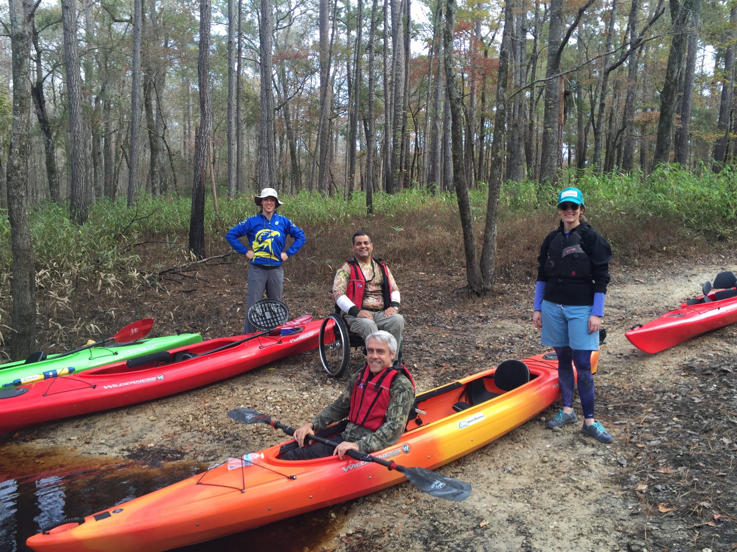 Group of people getting into kayaks smiling at the camera
