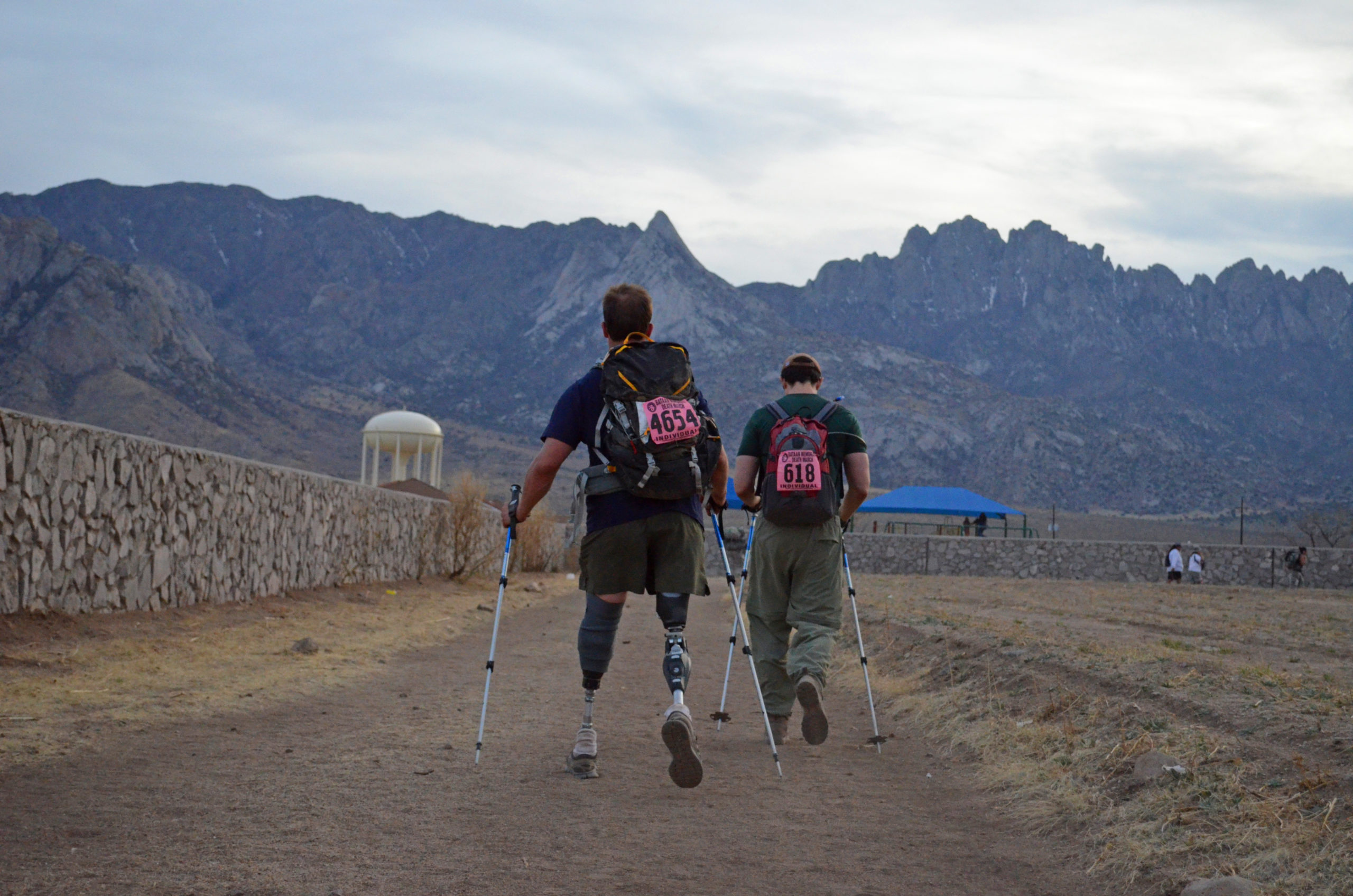 Two people hiking one with a double leg amputation with mountains in the background