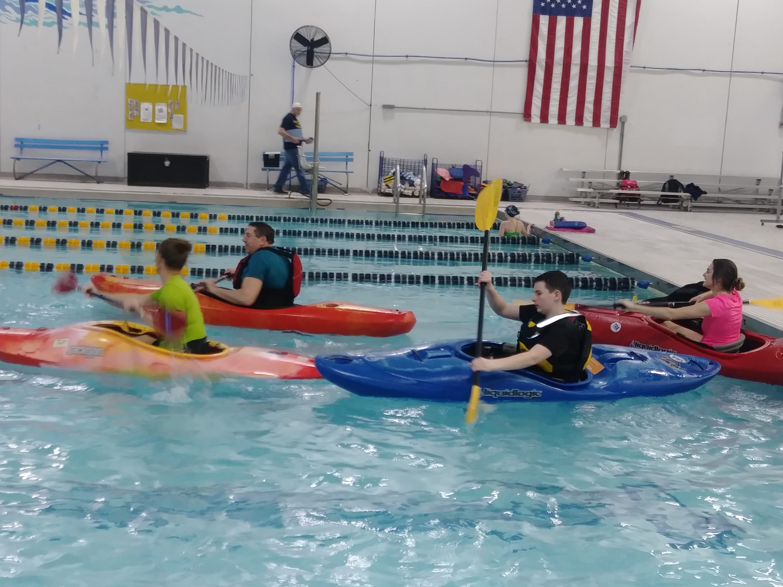 Four people in a swimming pool in kayaks