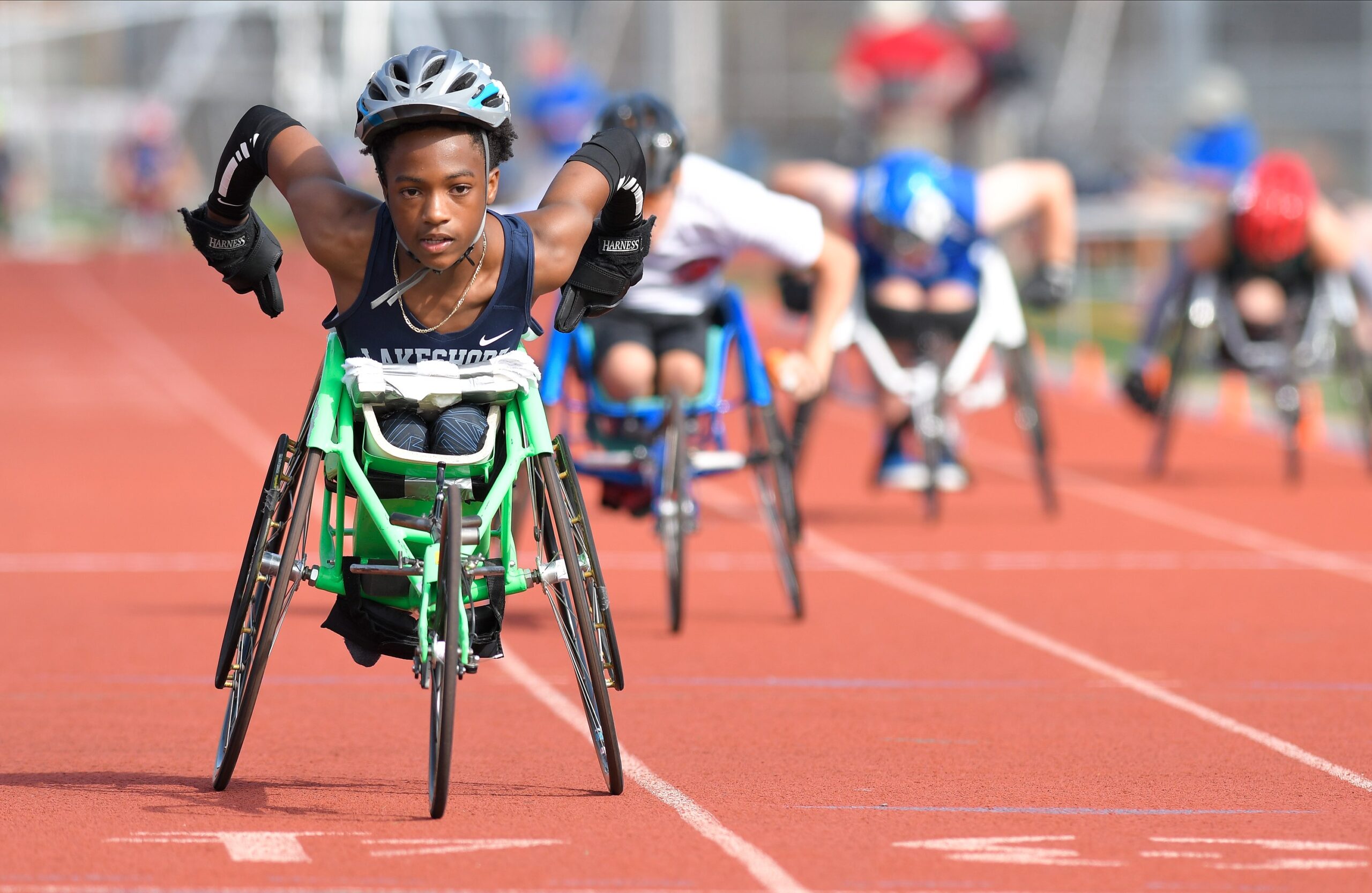 Athlete competing in racing wheelchair with other athletes behind them