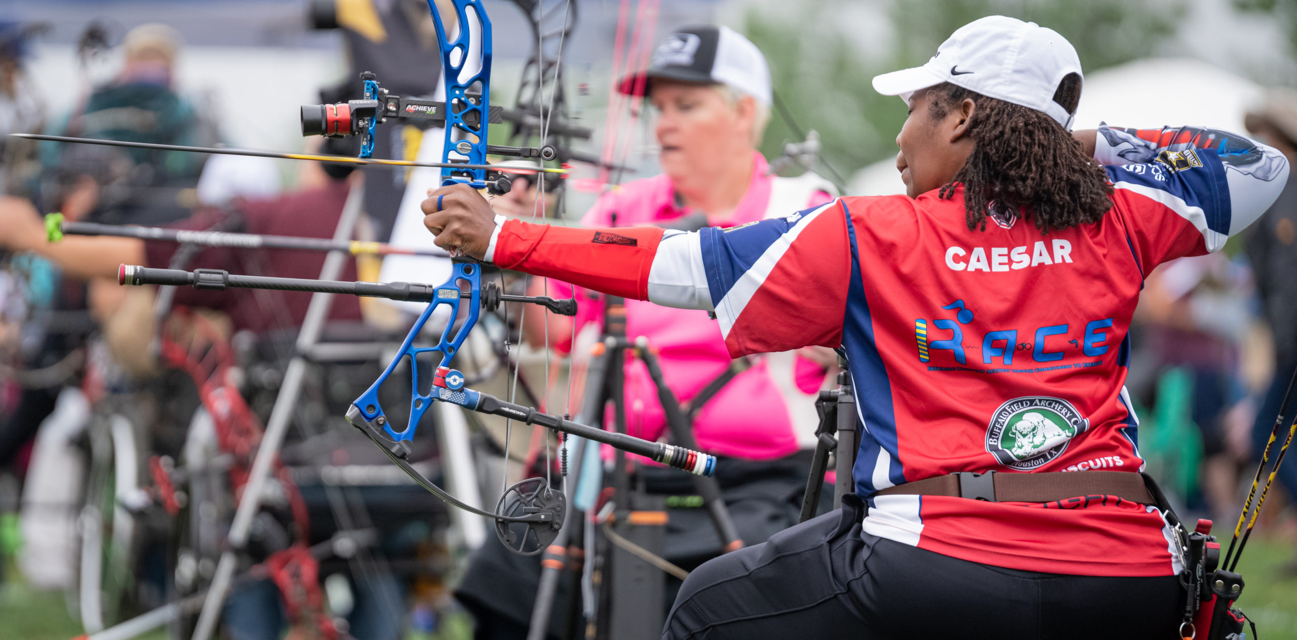 Black female seated athlete releasing arrow