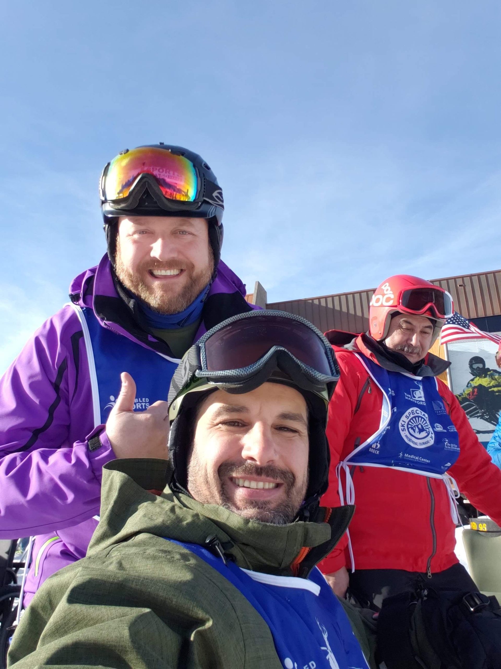 Three male skiers posed smiling at the camera and giving a thumbs up