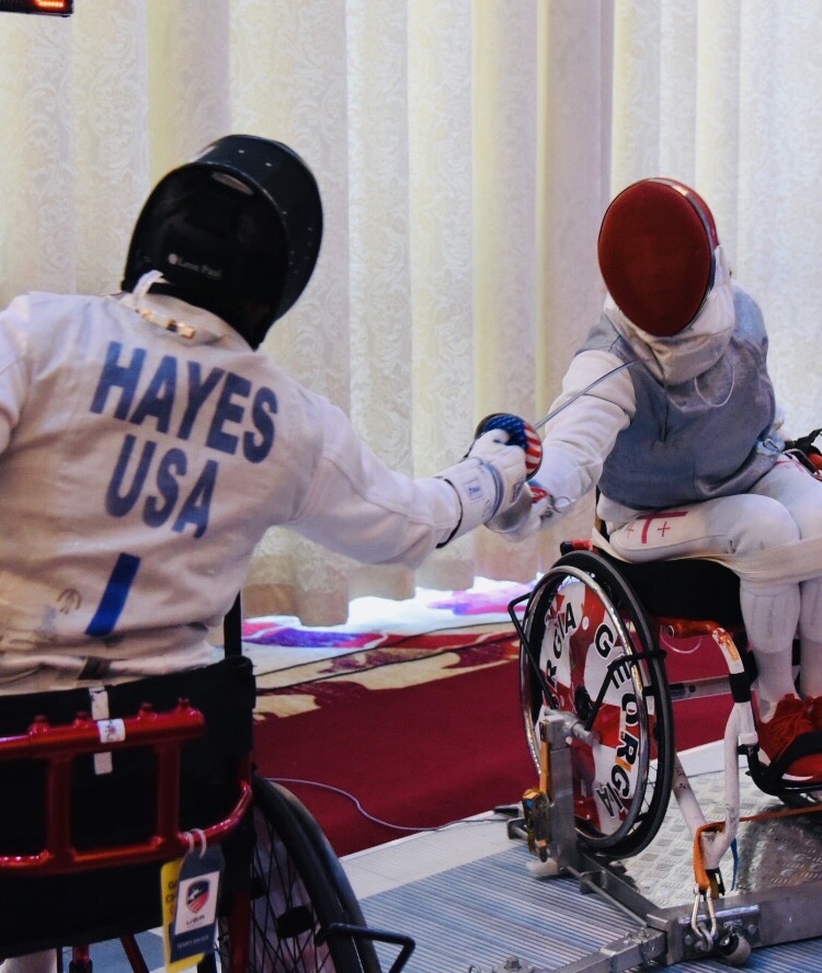 Two athletes in wheelchairs practicing fencing