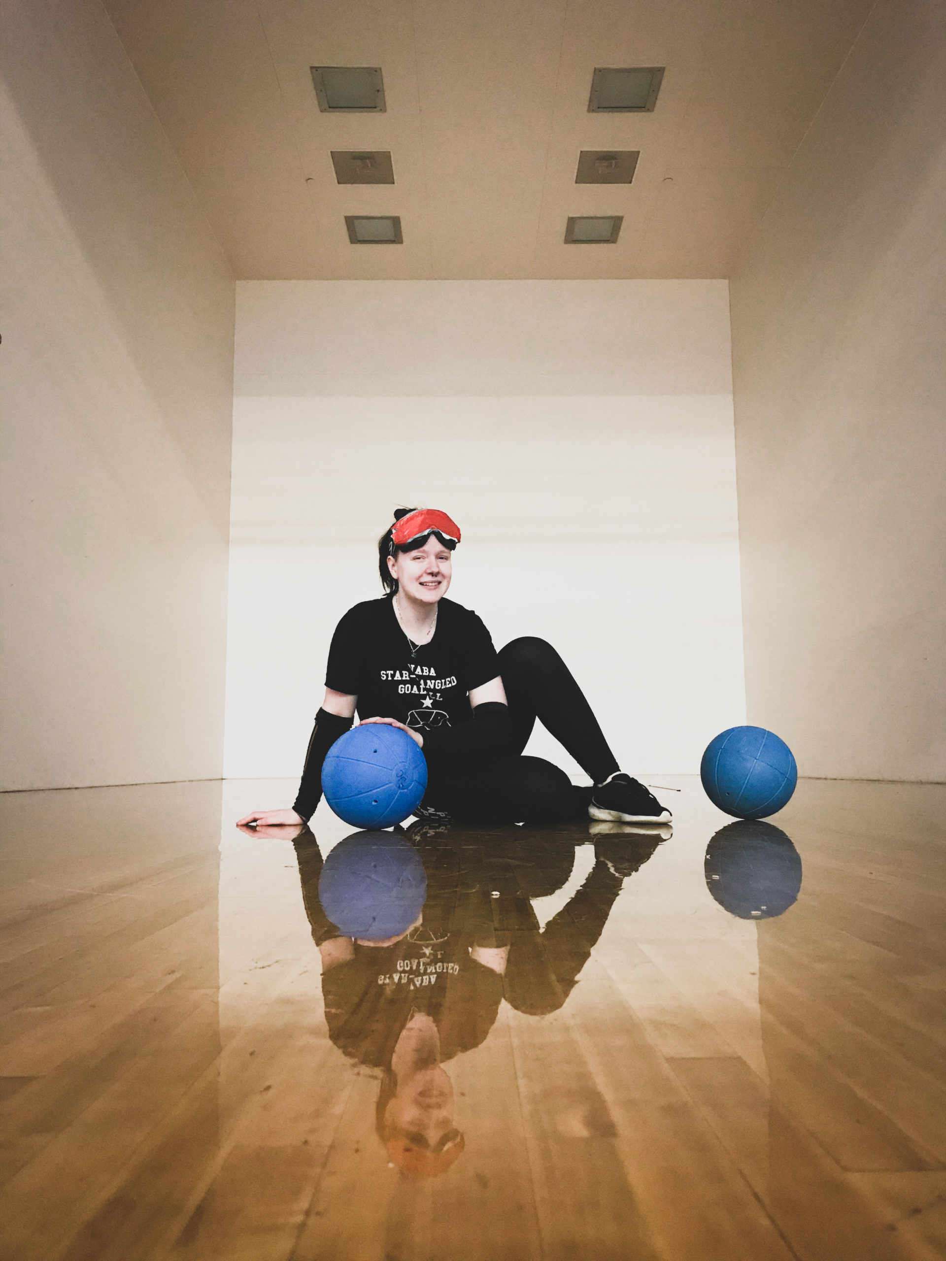 Female athlete sitting on the floor with two blue balls on the ground beside her