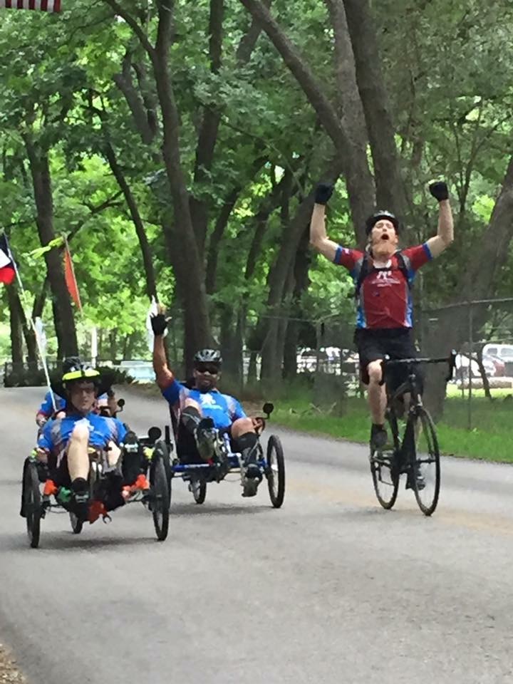 Athletes on bikes and adaptive bikes and smiling, waving, and celebrating towards the camera