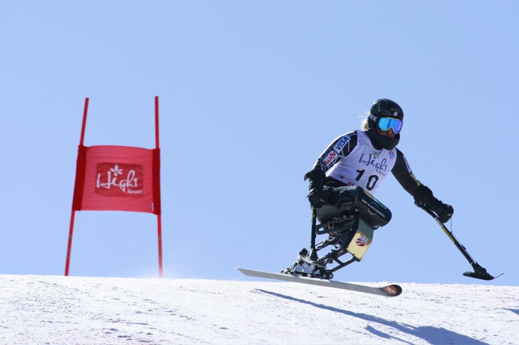 Skier on a mono-ski skiing past a banner