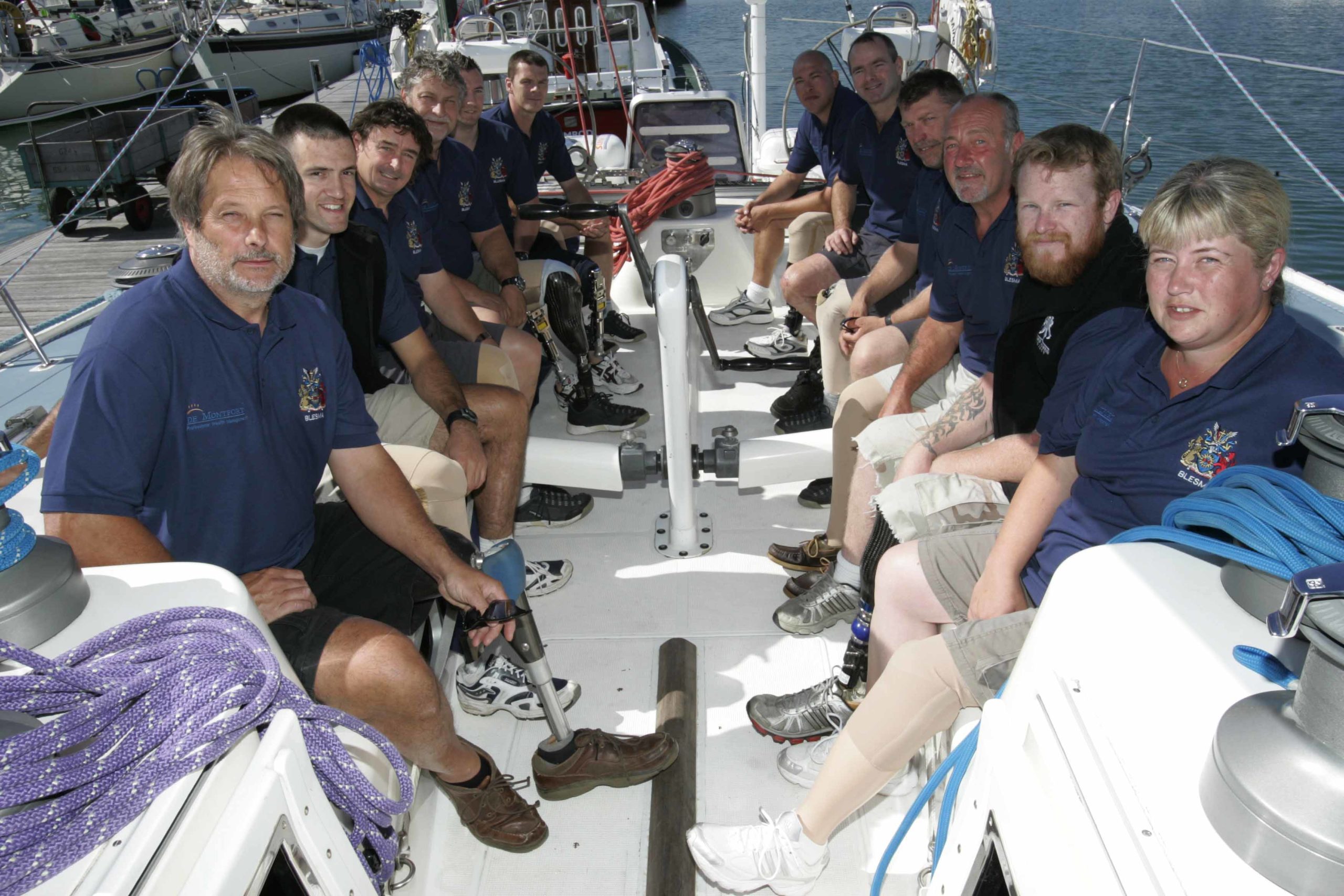 Group of Wounded Warrior participants sitting smiling at the camera on a sail boat