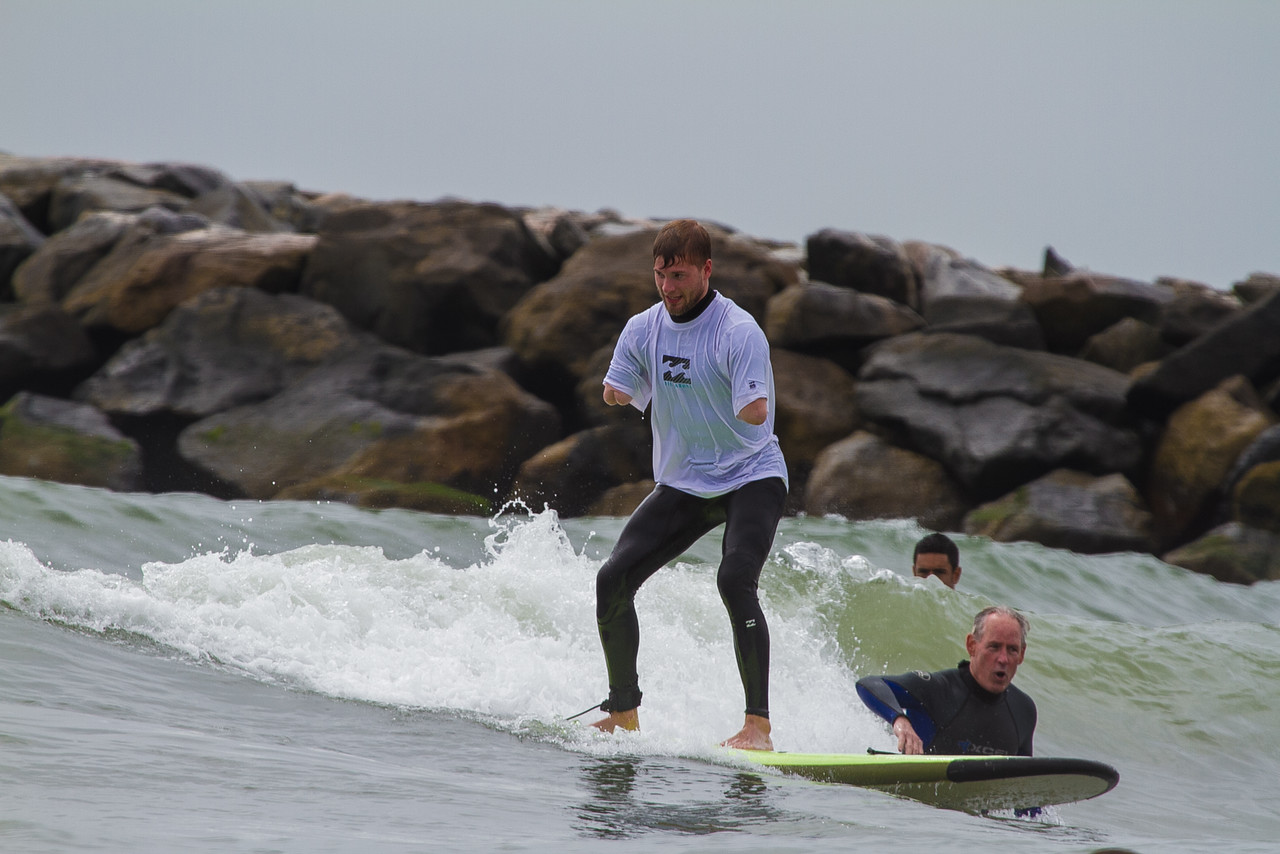 Male athlete with double arm below the elbow amputation standing on surfboard