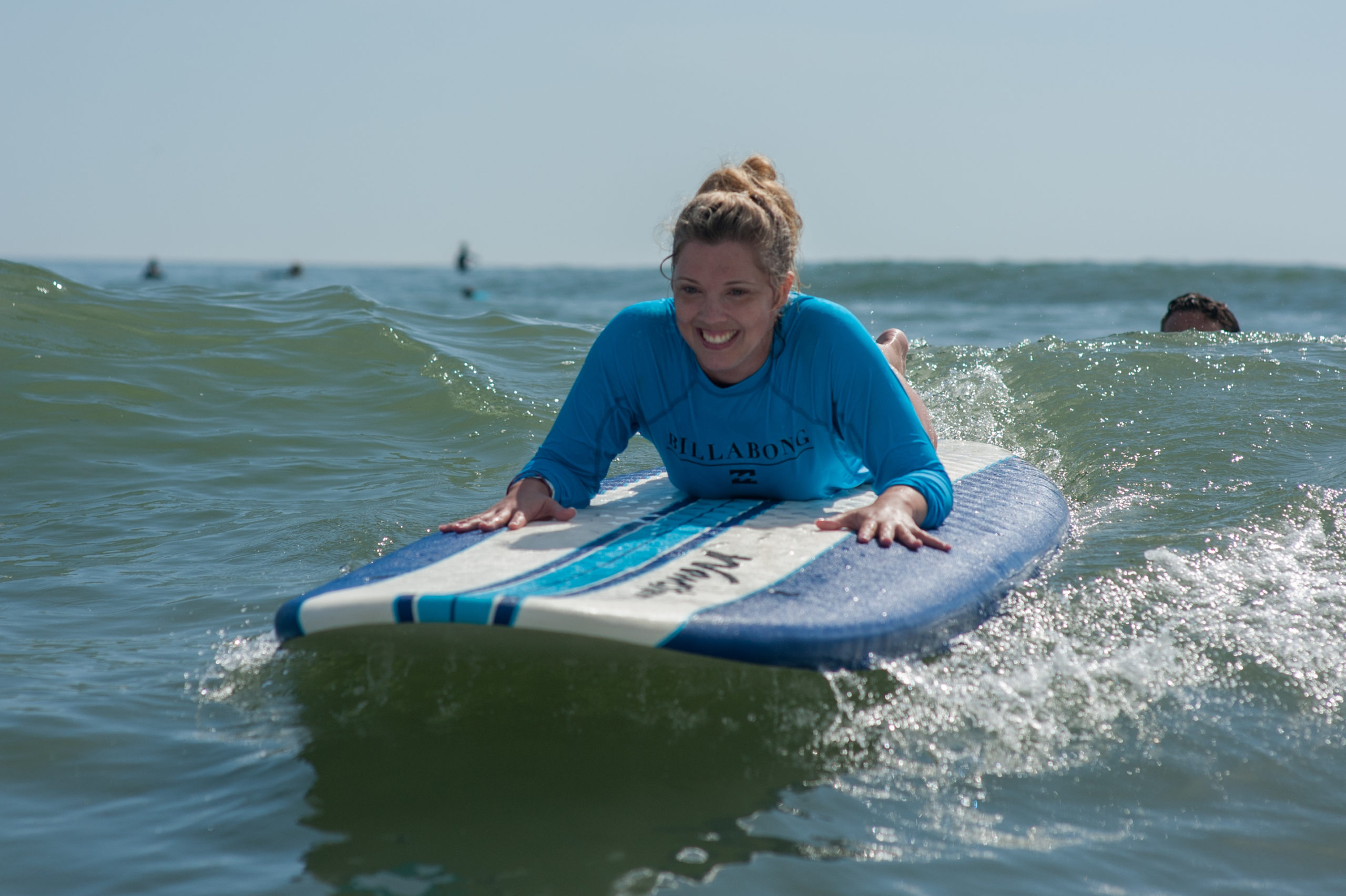 Female athlete laying on her stomach on her surfboard in the water