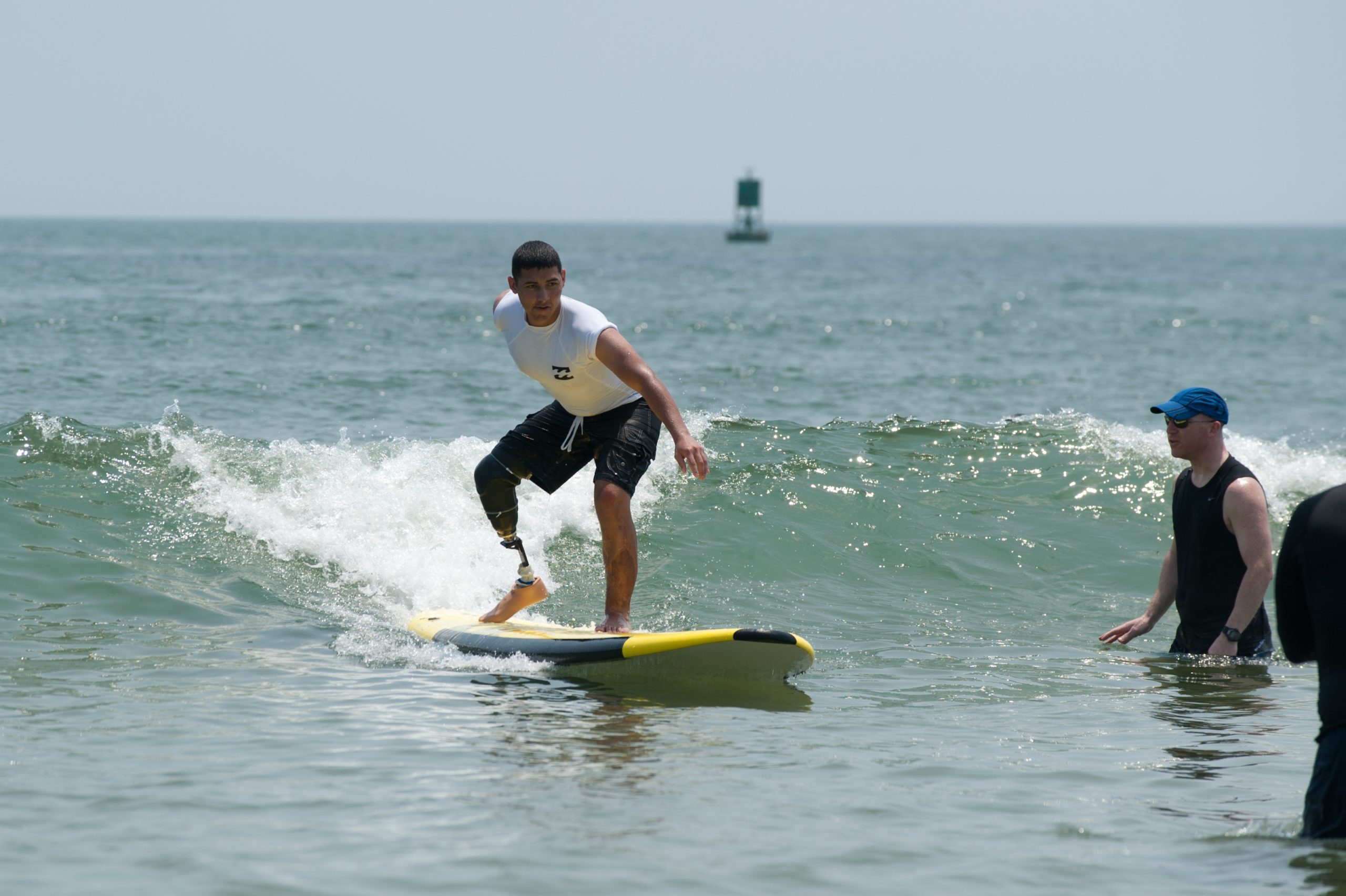 Male athlete with right leg prosthetic standing up on surfboard
