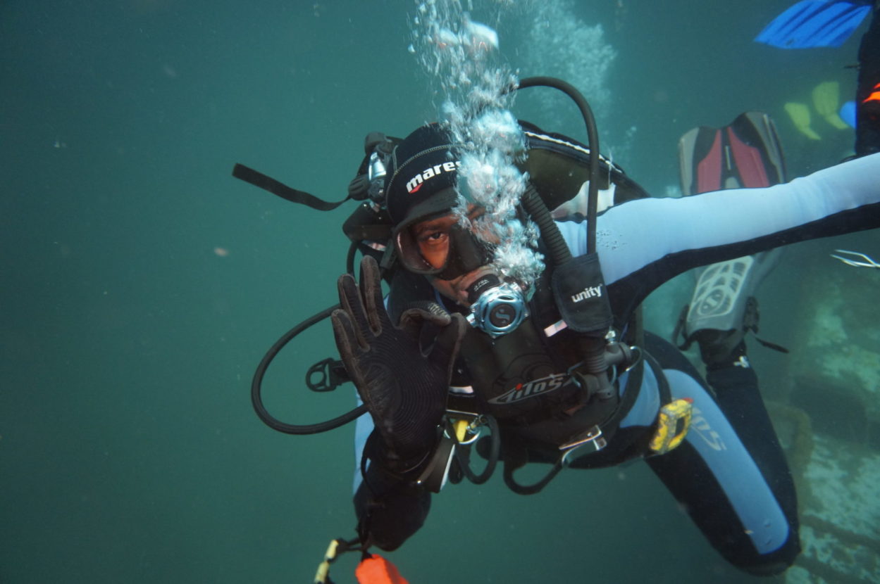 Scuba diver under water giving the okay hand signal to the camera