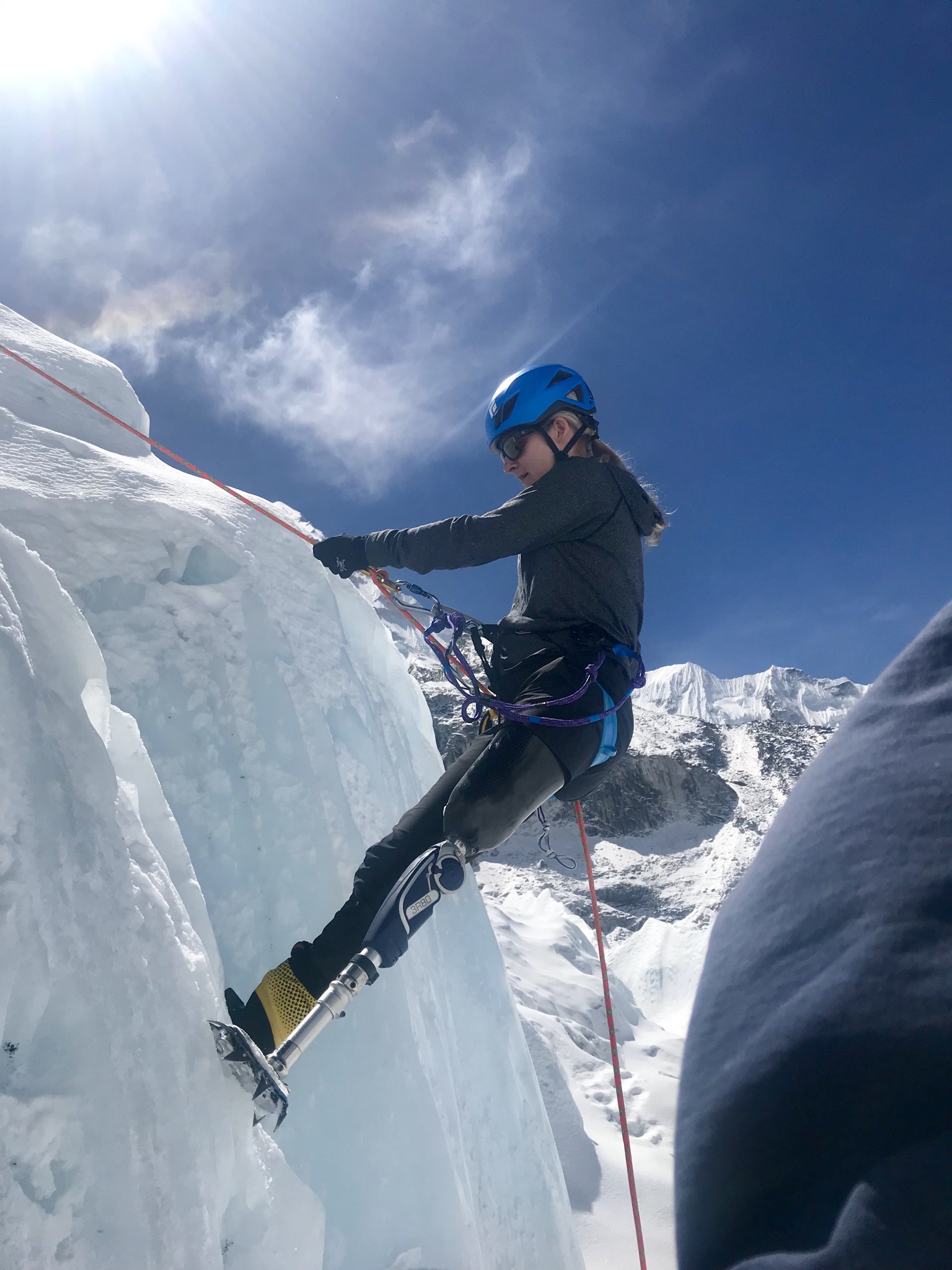 Athlete with left leg below the knee prosthetic climbing on a snow covered mountain