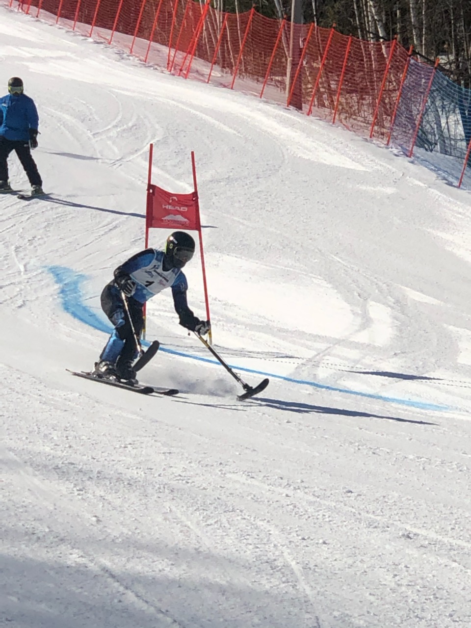 Athlete skiing with four track skis past a banner