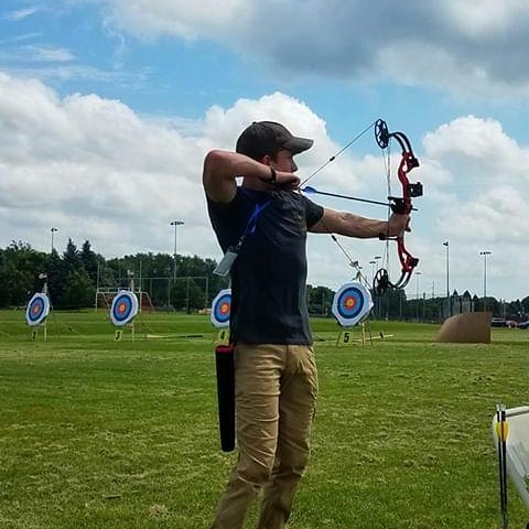 Male athlete aiming bow and arrow
