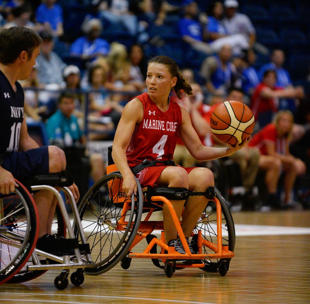 Female athlete looking at male athlete playing wheelchair basketball and holding the basketball