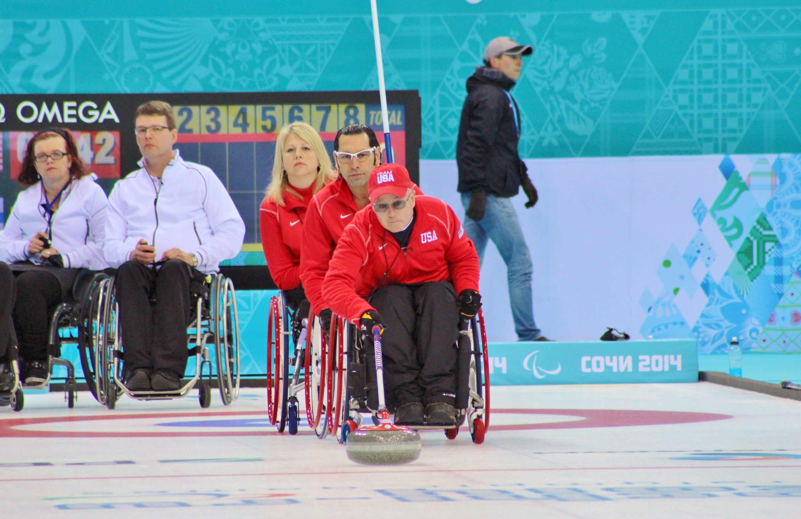 Group of athletes in wheelchairs watching another athlete curl