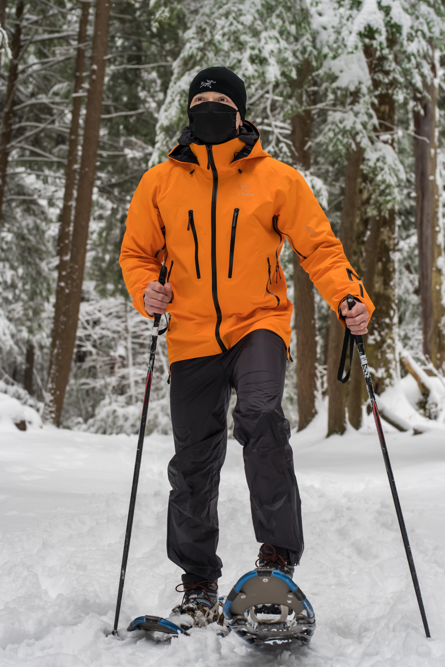 Male athlete in orange coat snowshoeing
