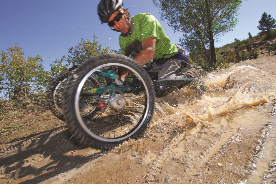 Athlete riding through mud on adaptive mountain bike