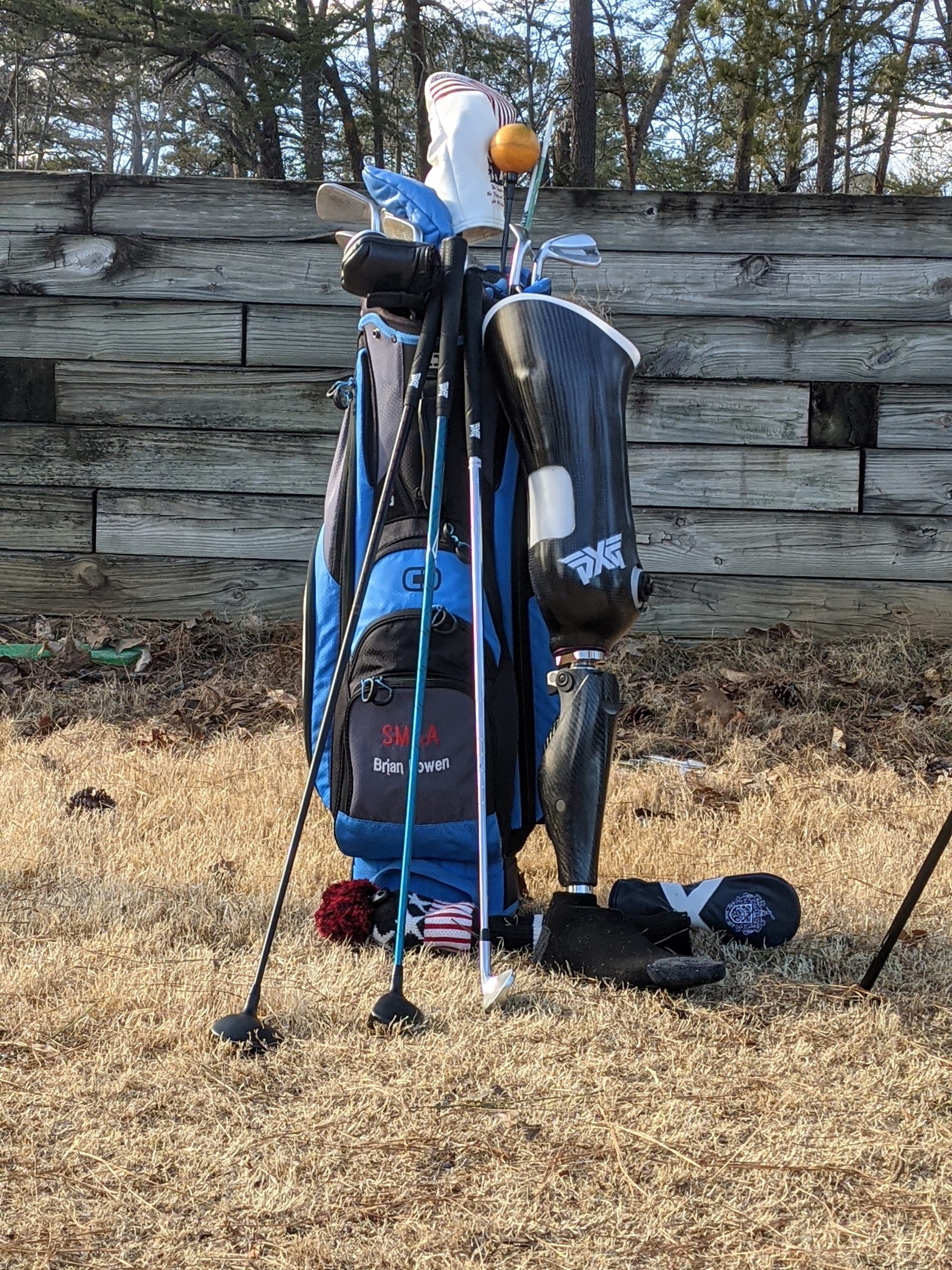 Blue golf bag with leg prosthetic leaning leaning upright on the bag