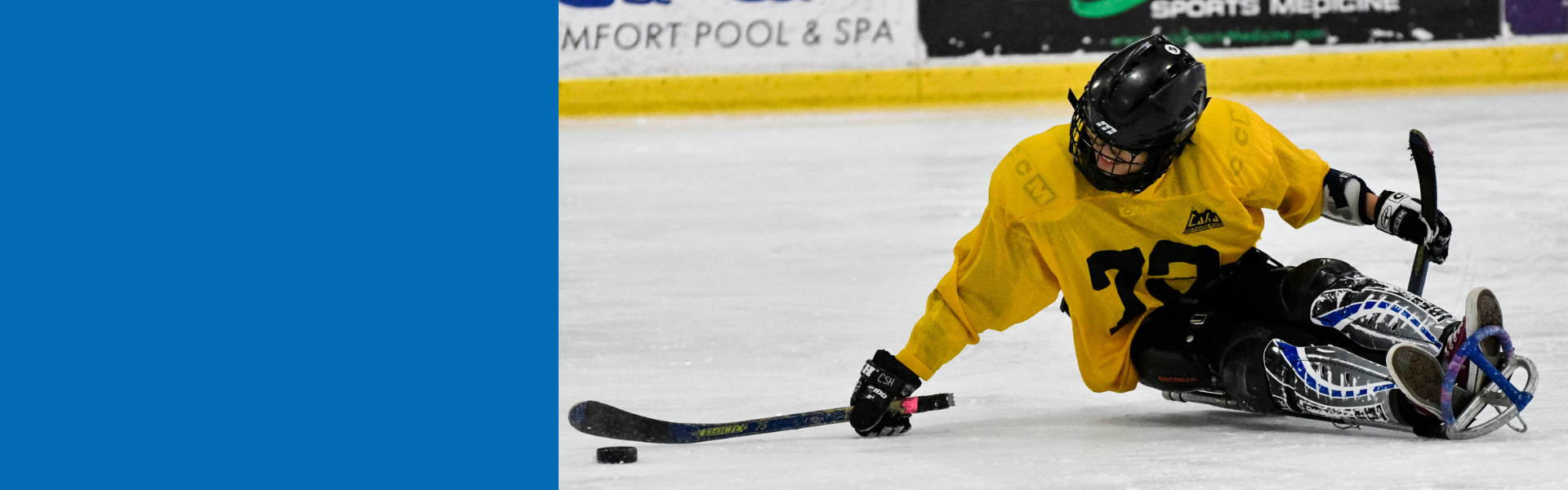 Close up of a person at an indoor ice rink participating in sled hockey