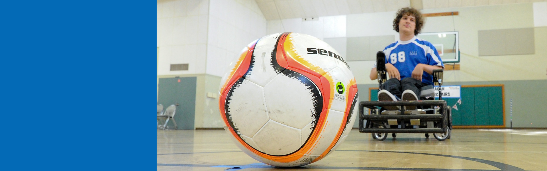 Close up of a soccer ball with a power soccer player in the background at an indoor court