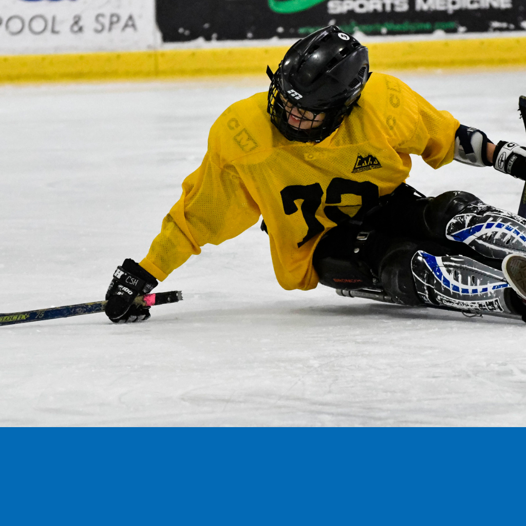 Close up of a person at an indoor ice rink participating in sled hockey