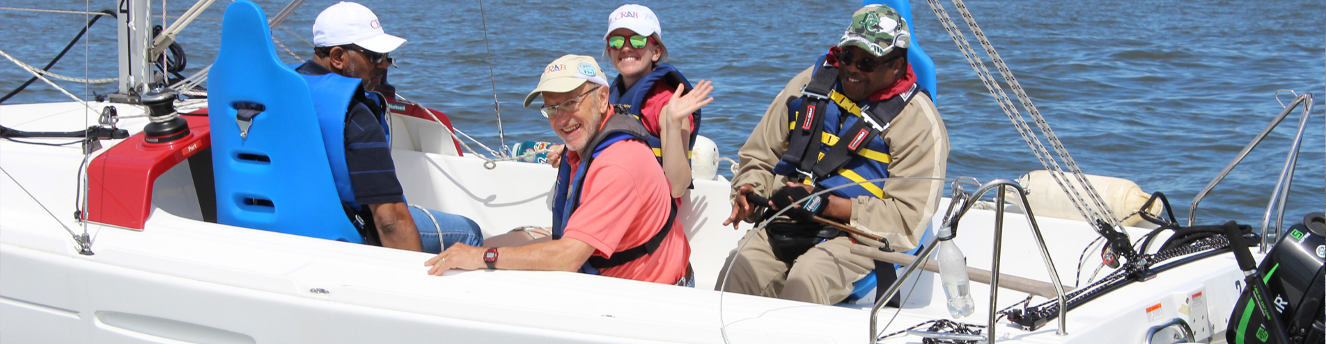 Group of people sitting in a boat smiling and waving at camera