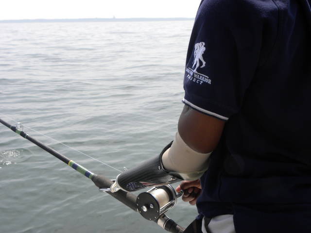 Athlete with left arm amputation below the elbow holding a fishing pole