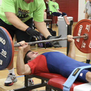 male athlete powerlifting with a spotter behind him