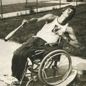 Black and white photo of male athlete in a wheelchair playing baseball