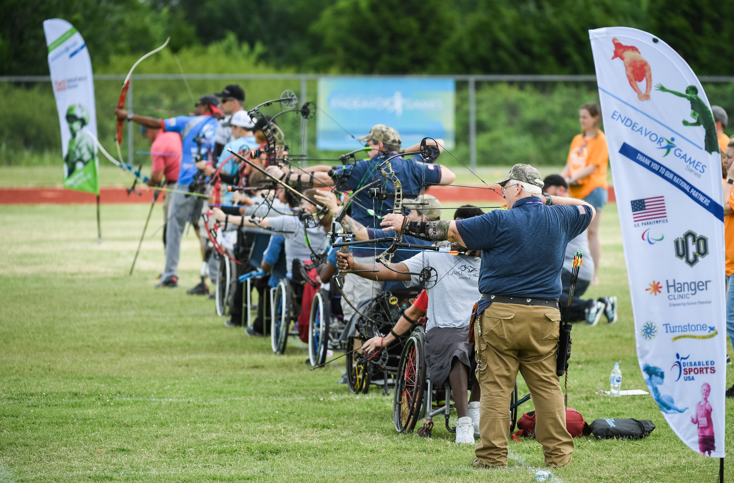 Athletes in wheelchairs and standing doing archery