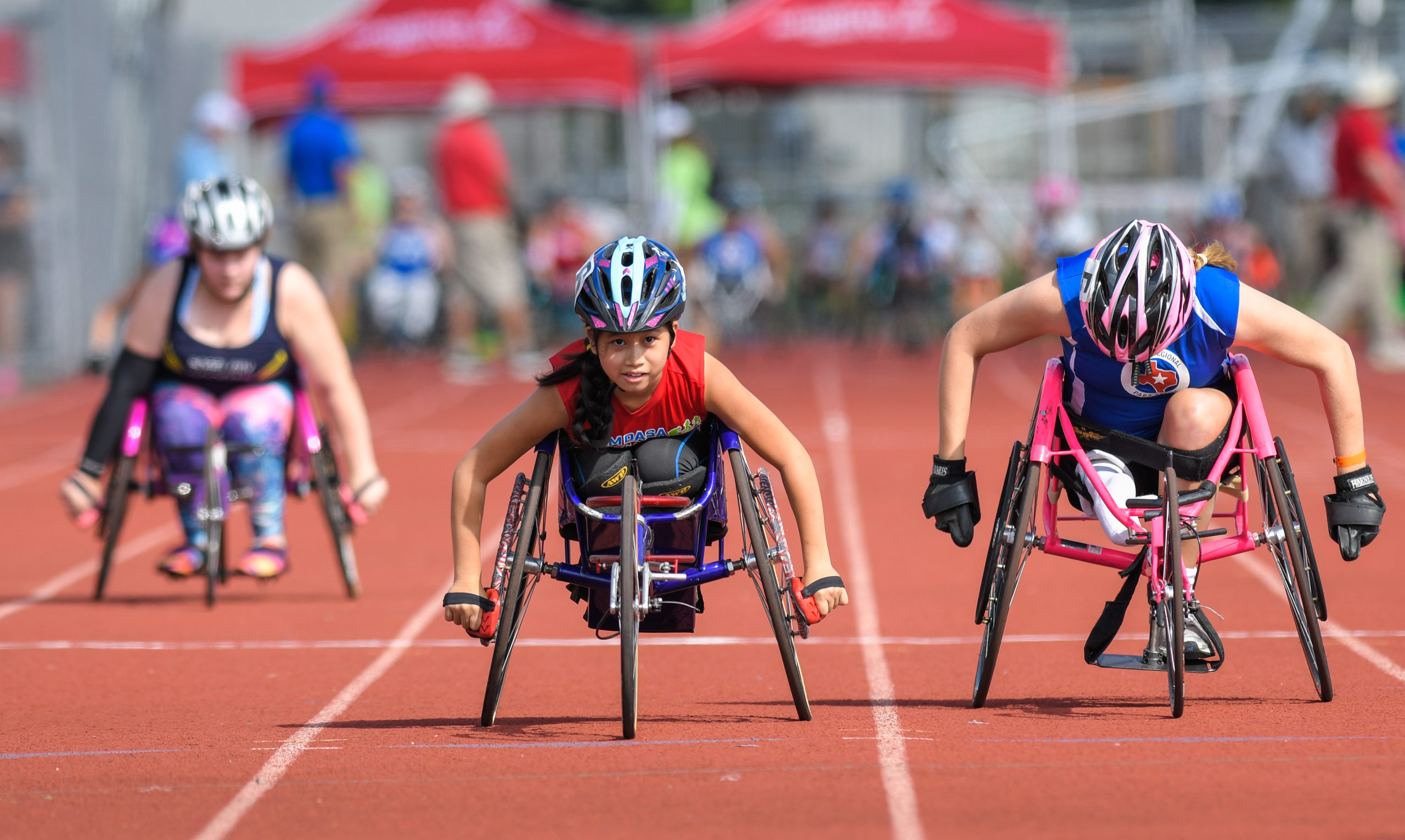 Three athletes competing in wheelchair racing