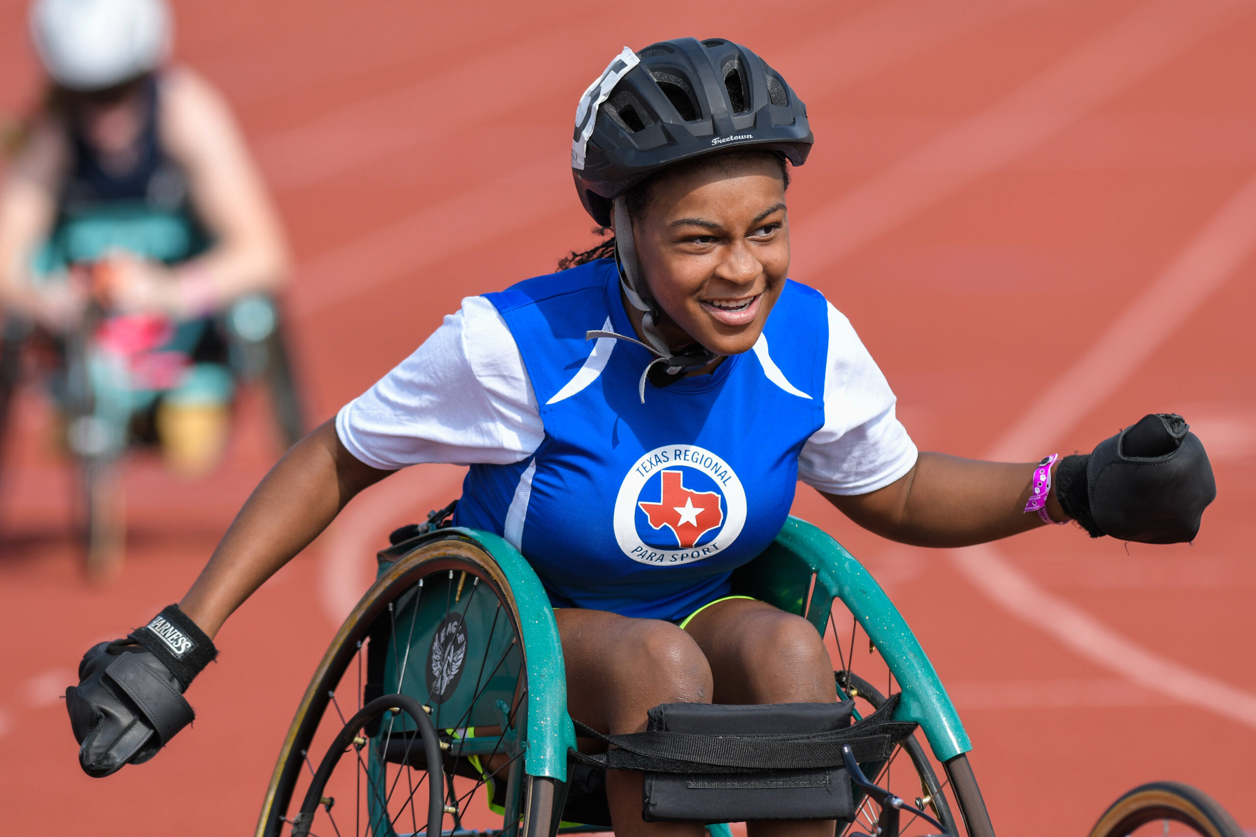 Female athlete in a racing wheelchair smiling