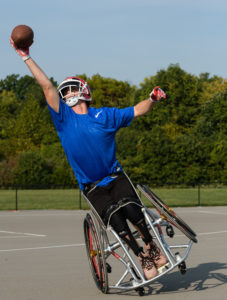 Male athlete in a wheelchair reaching for a football