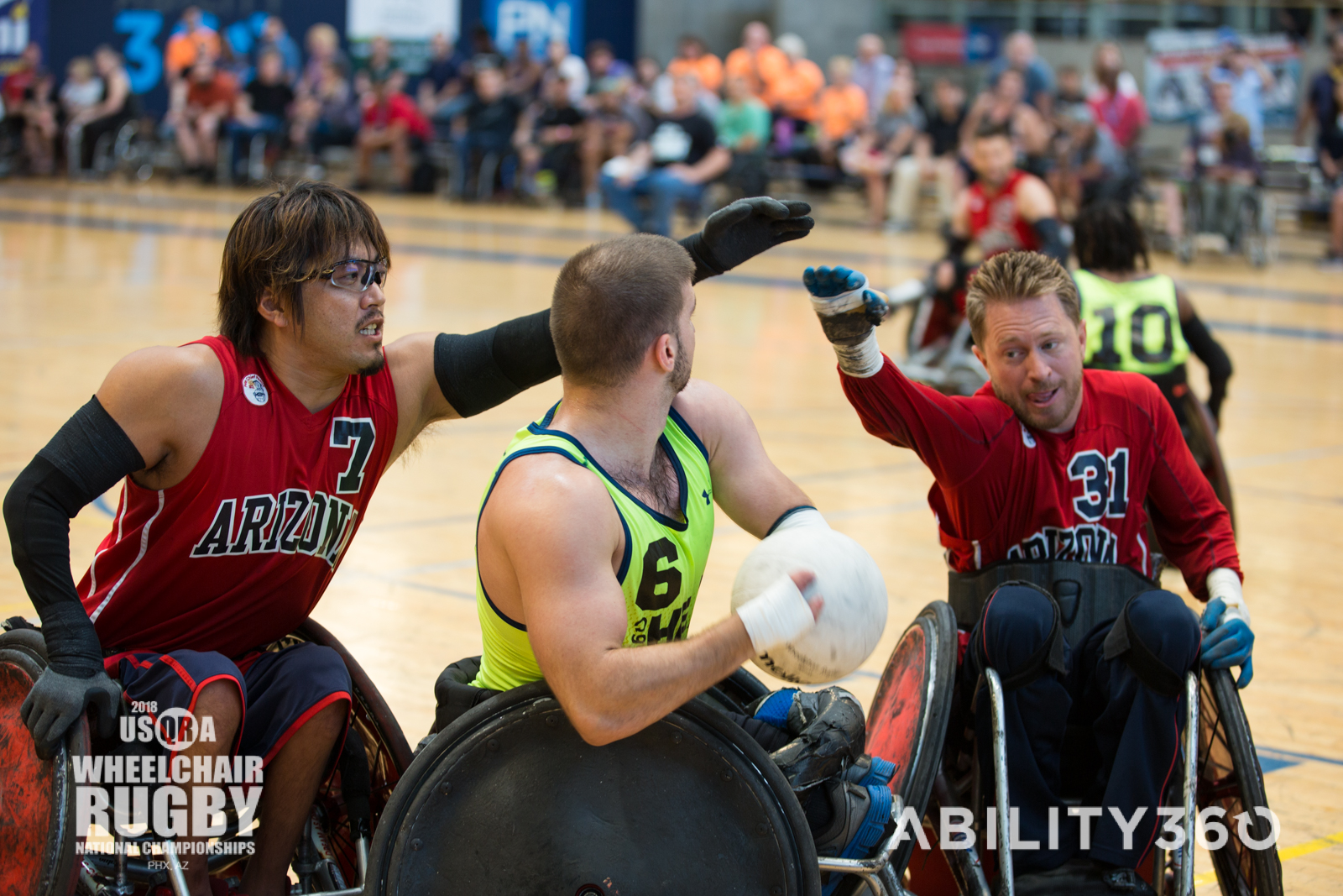 Three athletes playing wheelchair rugby