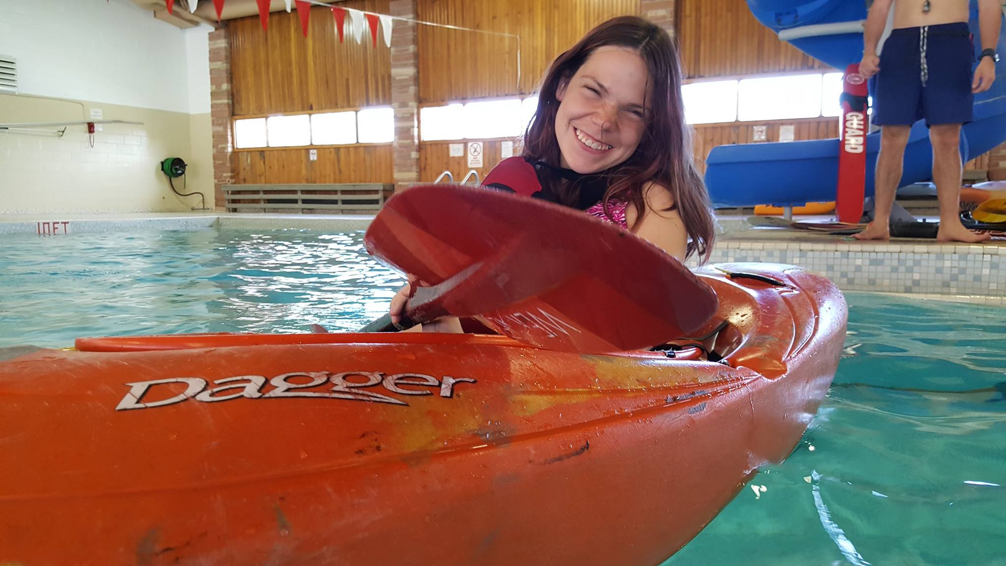 Athlete in kayak in swimming pool smiling at camera
