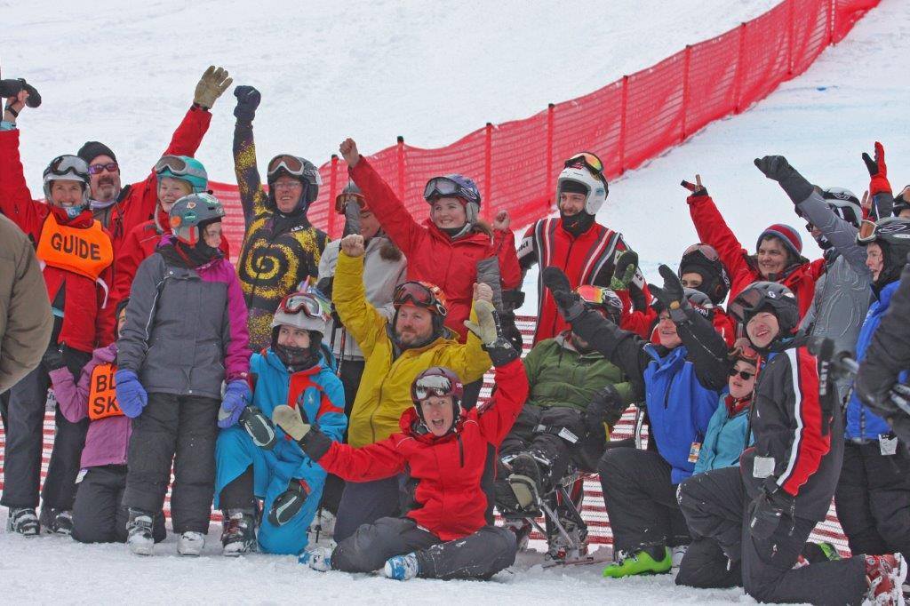 Group of athletes in snow clothing with their arms raised smiling