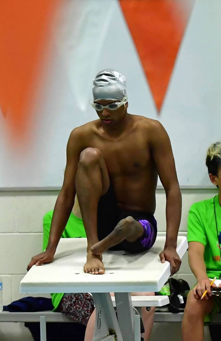 athlete with limb differnce on swimming pool starting platform