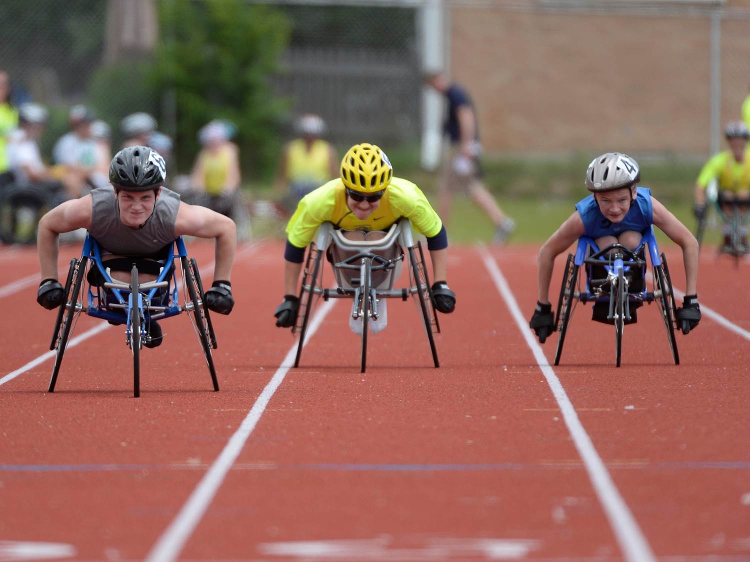 Three athletes racing in racing wheelchairs