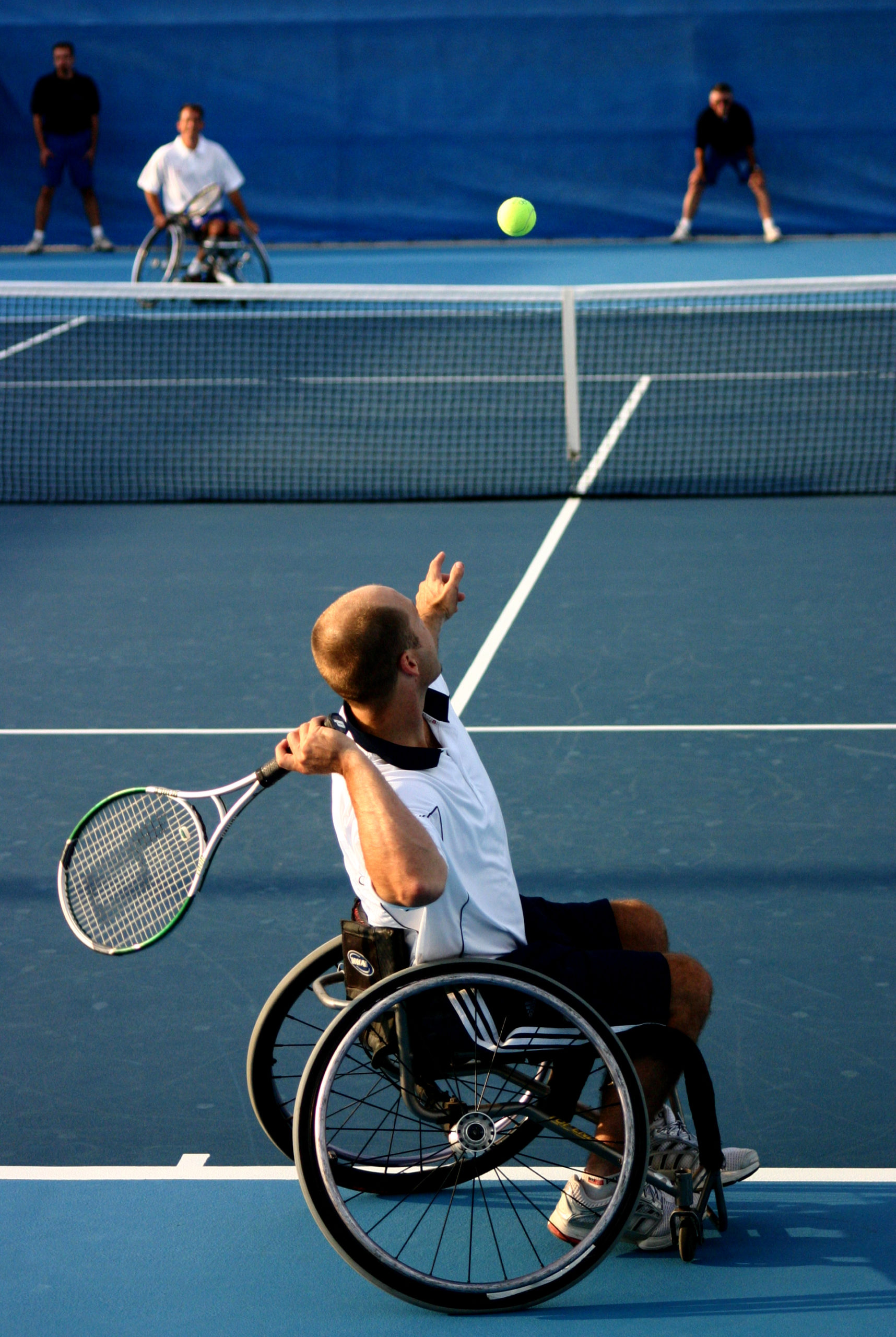 Male athlete in wheelchair playing tennis about to hit a tennis ball