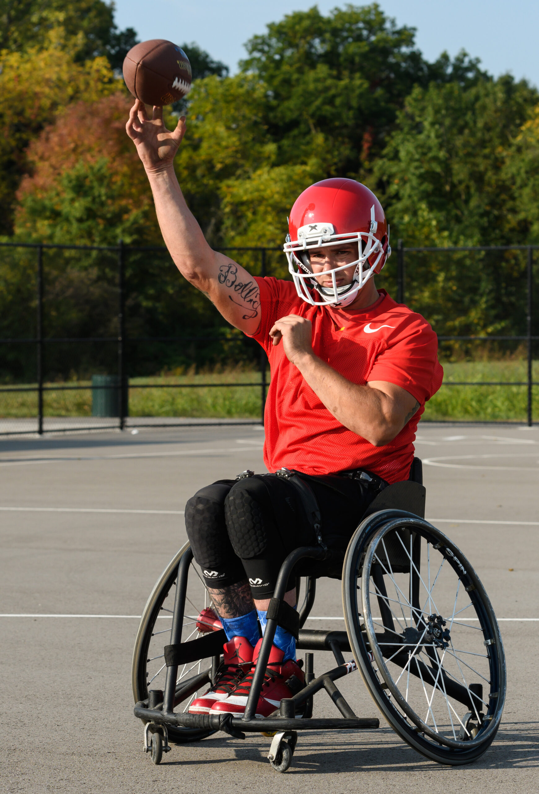Athlete in wheelchair throwing football outside