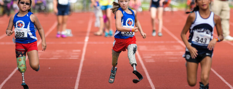 Three young female athletes with prosthetics running in a race