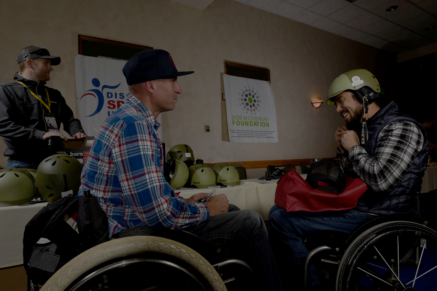 Two athletes in wheelchairs smiling and talking to each other