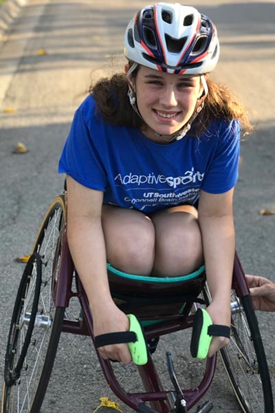 Female athlete in racing wheelchair smiling at camera