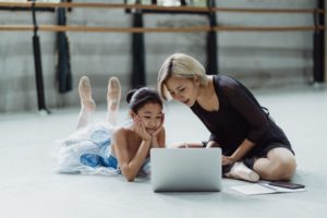 Dance instructor and ballerina student looking at computer screen