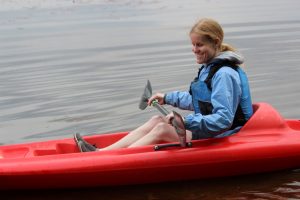 Female athlete with visual impairment kayaking on lake
