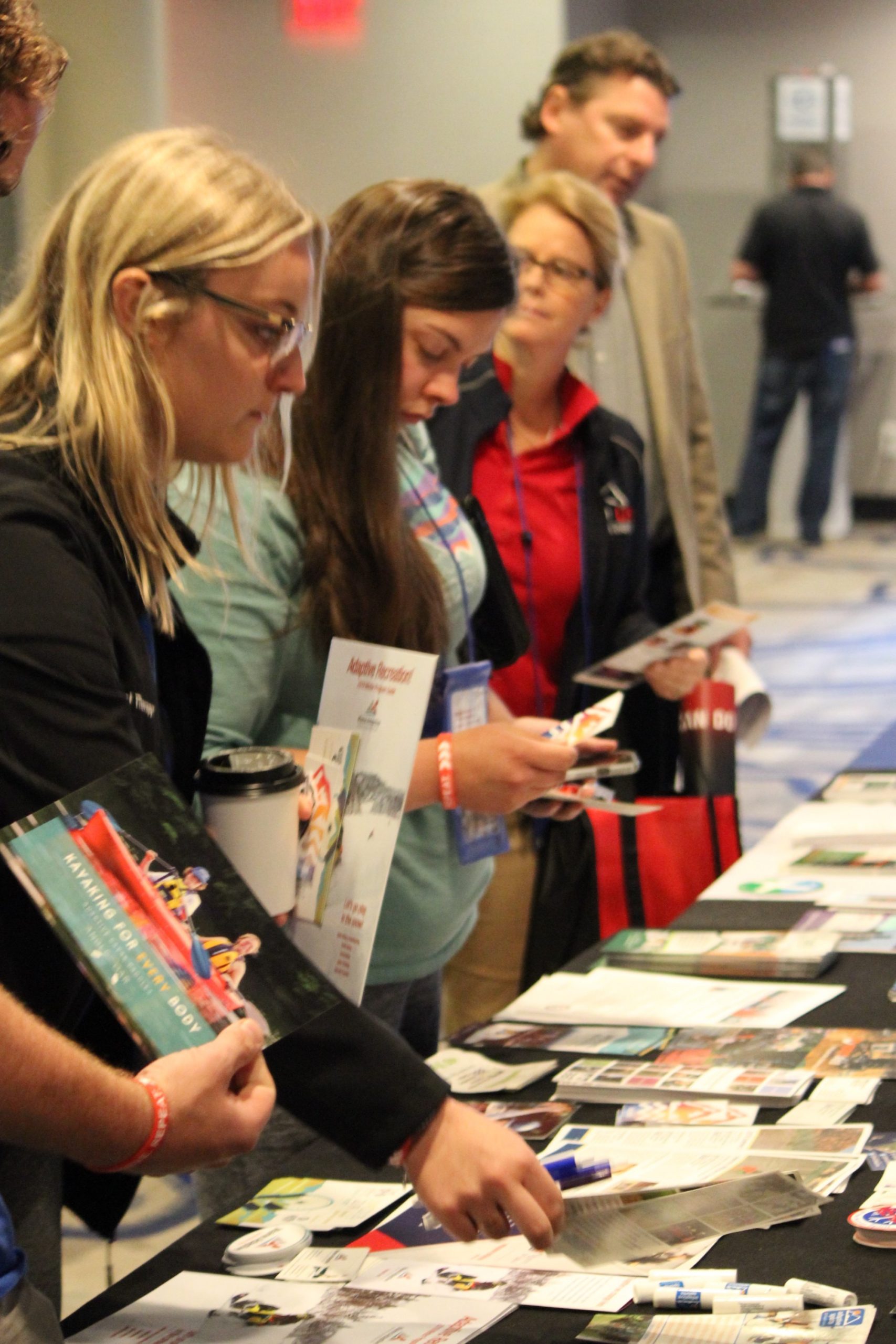 3 women standing in front of a a table with brochures and pamphlets